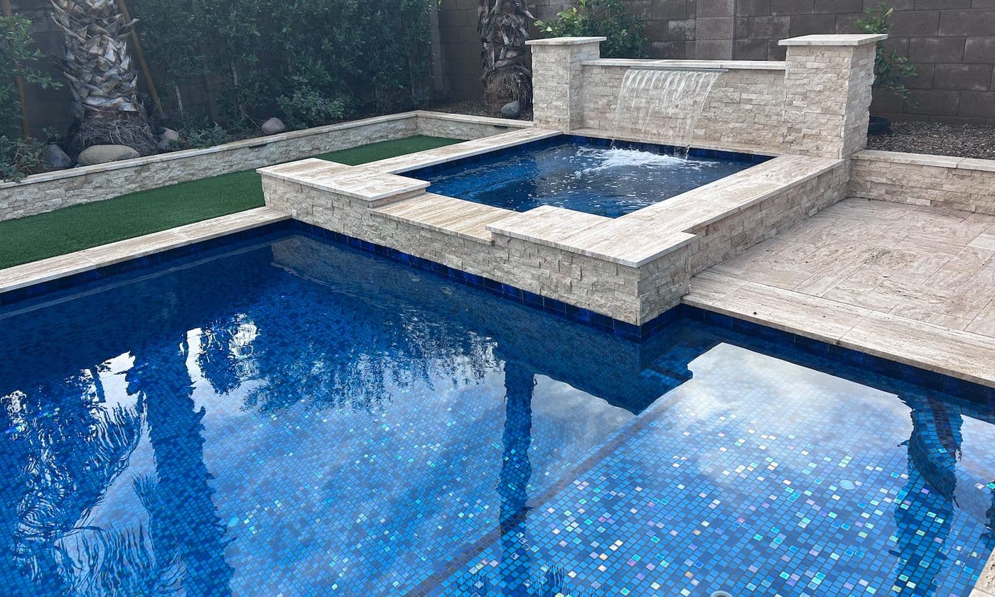 Remodeled pool with raised spa and a wide stacked-stone waterfall